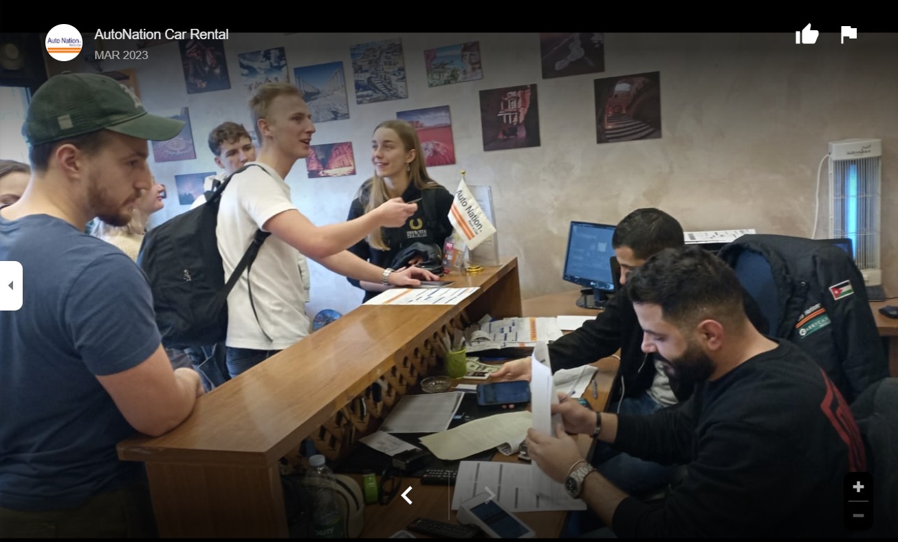 auto Car Rental staff member showing customers car rental reviews 